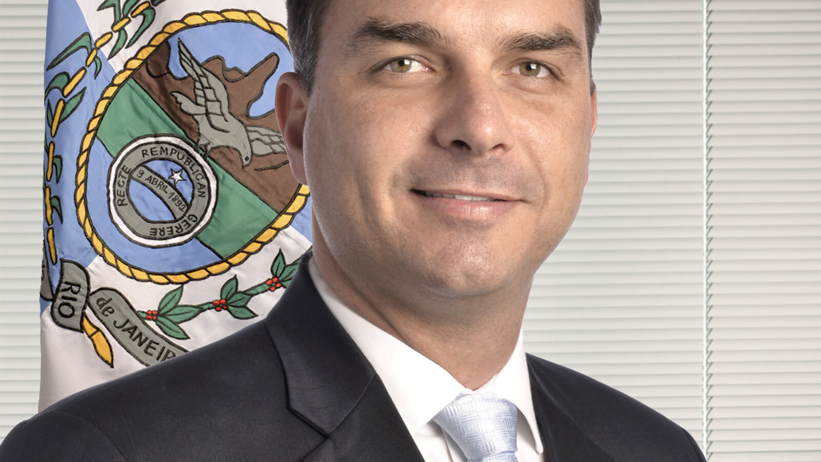 Flávio Bolsonaro, senador pelo Rio, de terno escuro e gravata clara, sorrindo em retrato oficial.