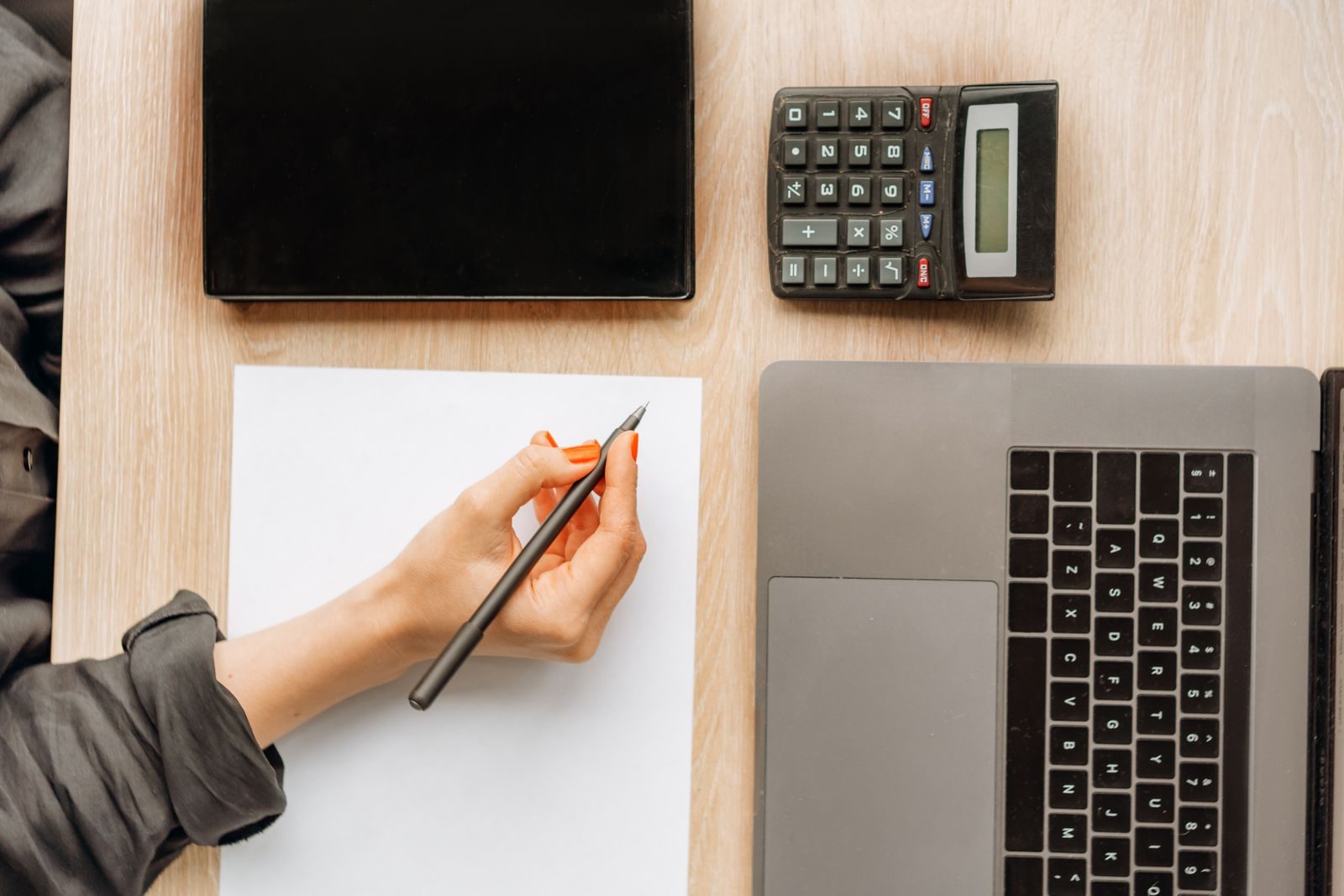 Profissional usa calculadora e notebook para avaliar o custo de assinaturas digitais