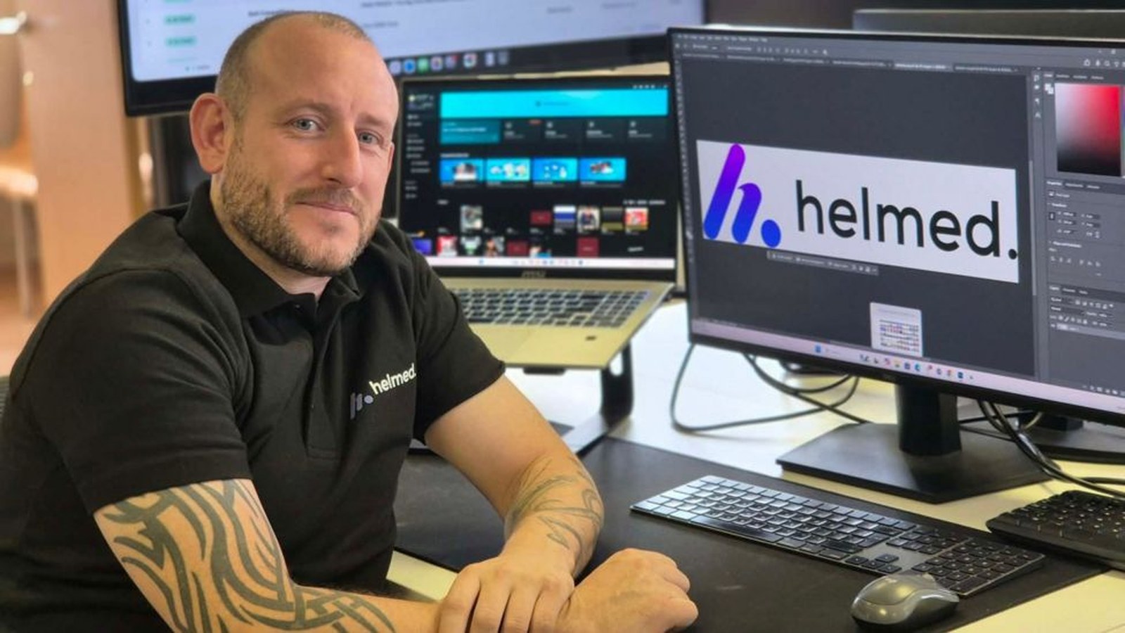O designer gráfico Danny Williams, de East Yorkshire, sentado à mesa com vários monitores.