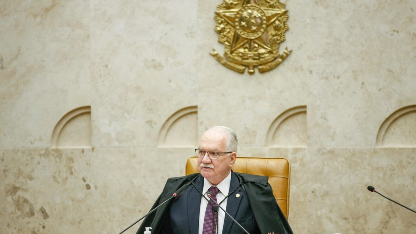 Edson Fachin, presidente do STF, de toga, sentado à mesa do plenário do Supremo