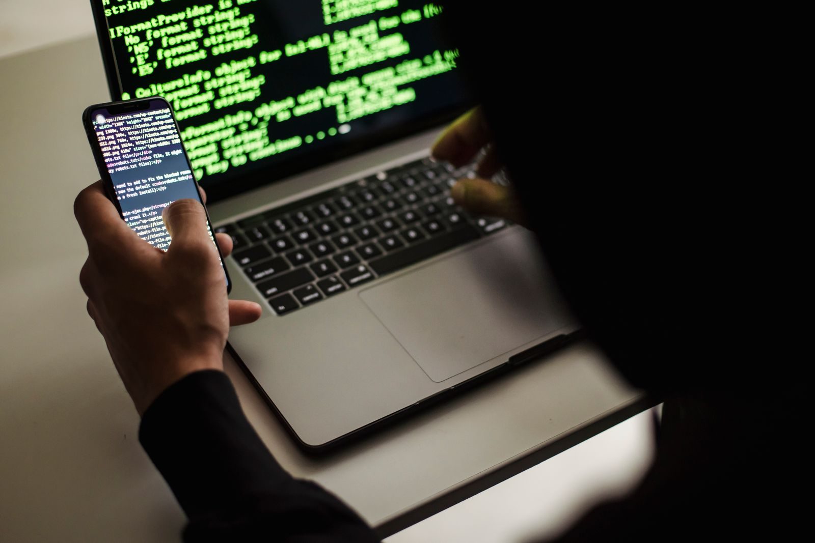 Pessoa em frente a um notebook com linhas de código na tela