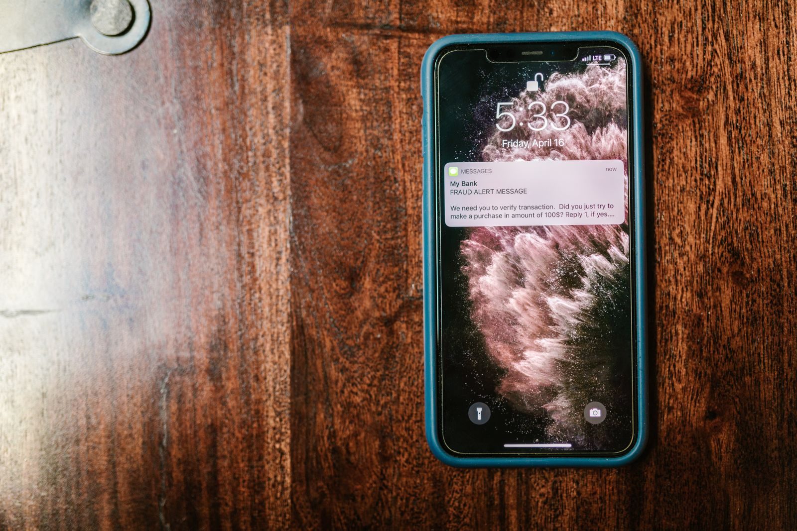 Mão segurando smartphone com ícone de segurança digital sobre tela de aplicativo bancário