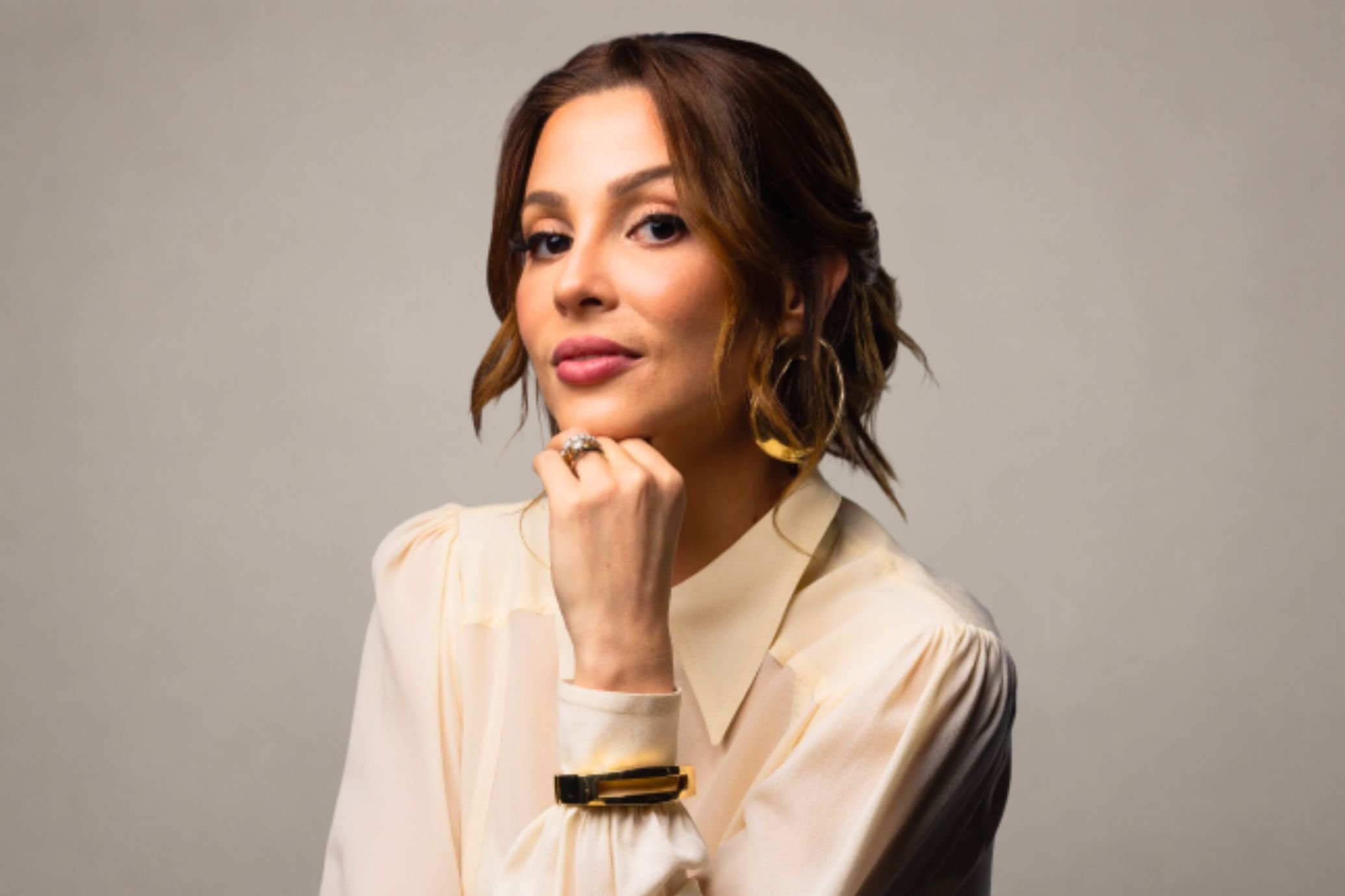 Priscila Zillo Sobral, CEO do Grupo Permaneo, de blusa clara, mão no queixo, em retrato de estúdio