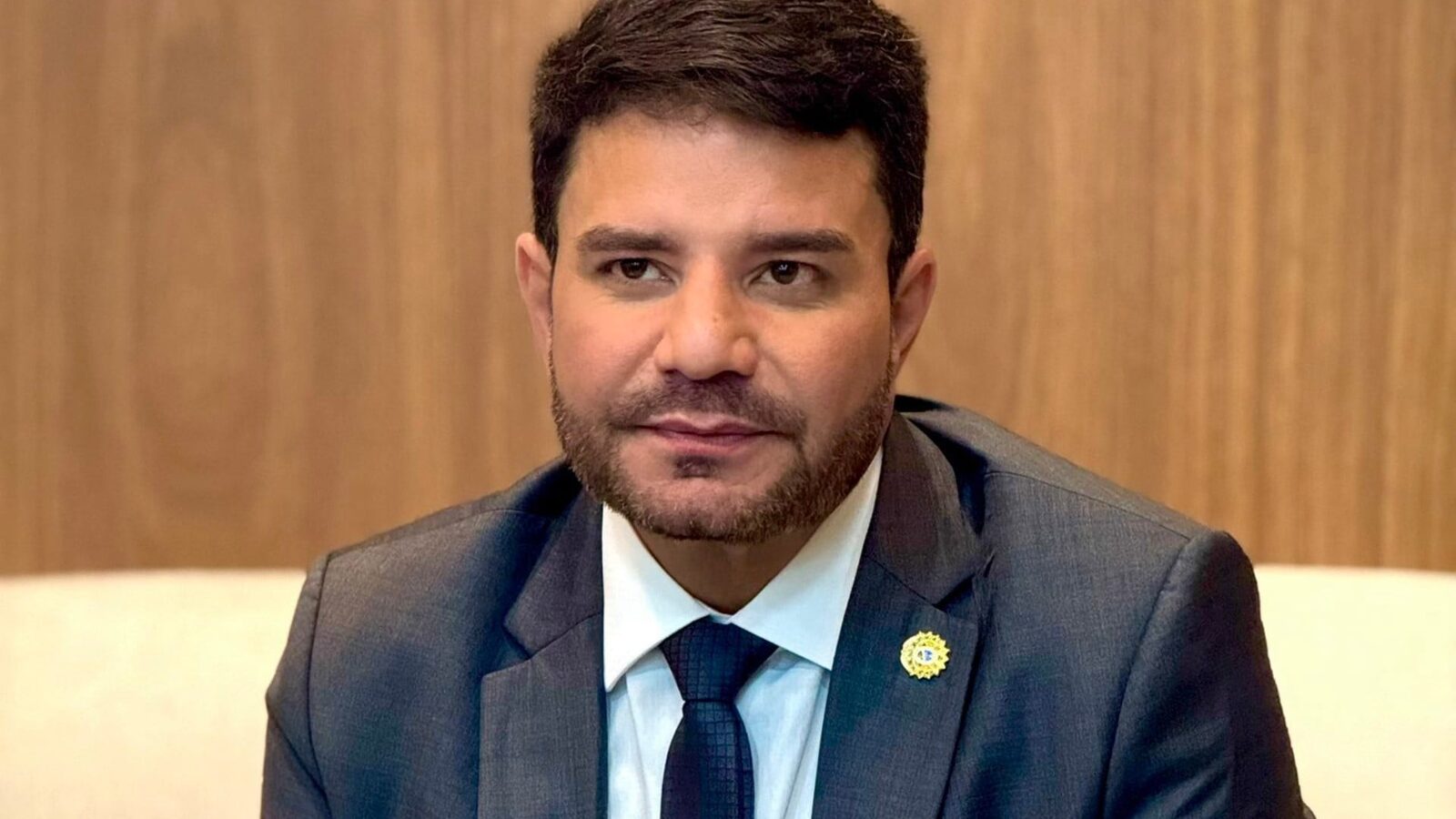 Gladson Cameli, ex-governador do Acre, de terno cinza e gravata, sentado em sofá